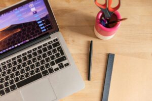 Modern laptop computer on wooden desk with coffee cup and notebook for social media management work