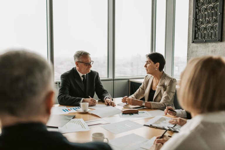 Professionals engaged in animated discussion around conference table during team meeting