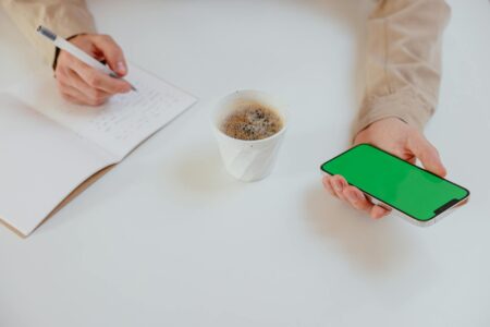 Person using smartphone while holding coffee cup, representing mobile ordering habits