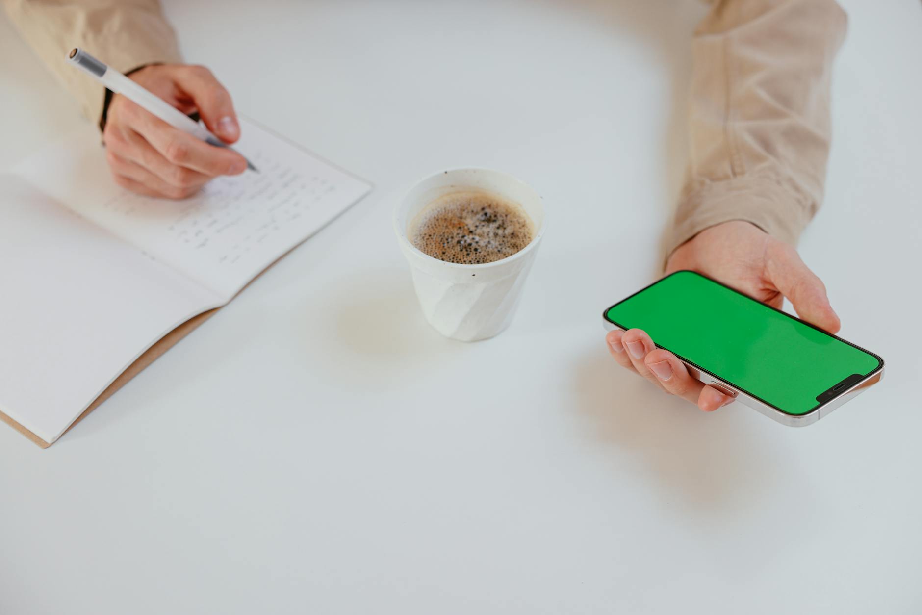 Person using smartphone while holding coffee cup, representing mobile ordering habits