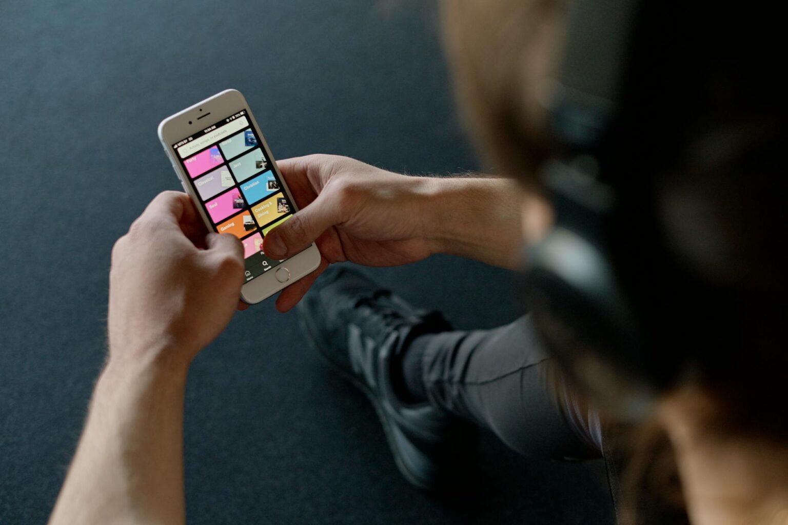 Person wearing headphones while using music streaming app on smartphone