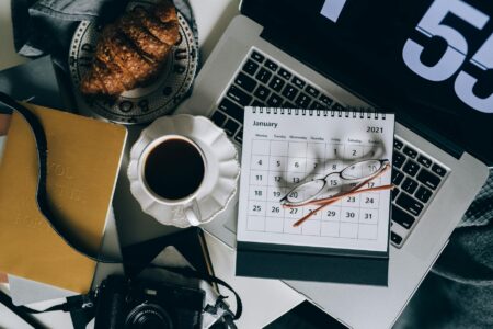 Person planning social media content calendar on laptop with colorful sticky notes and scheduling interface visible on screen