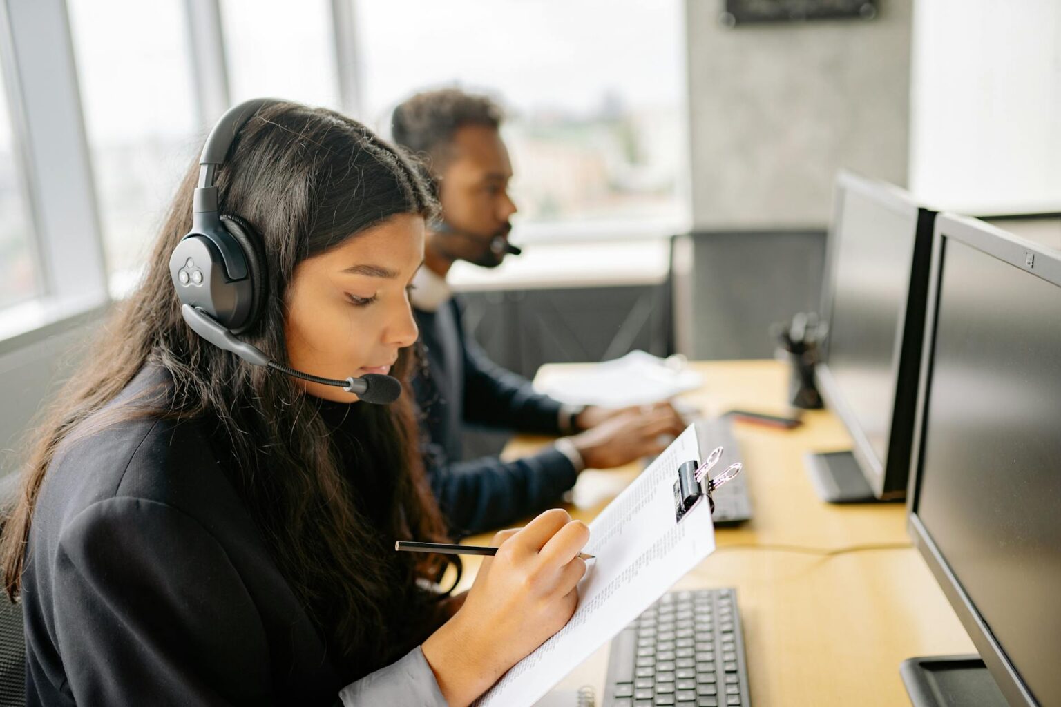 Professional customer service representative wearing headset while working at computer