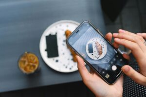 Person holding smartphone while ordering coffee, representing mobile ordering convenience