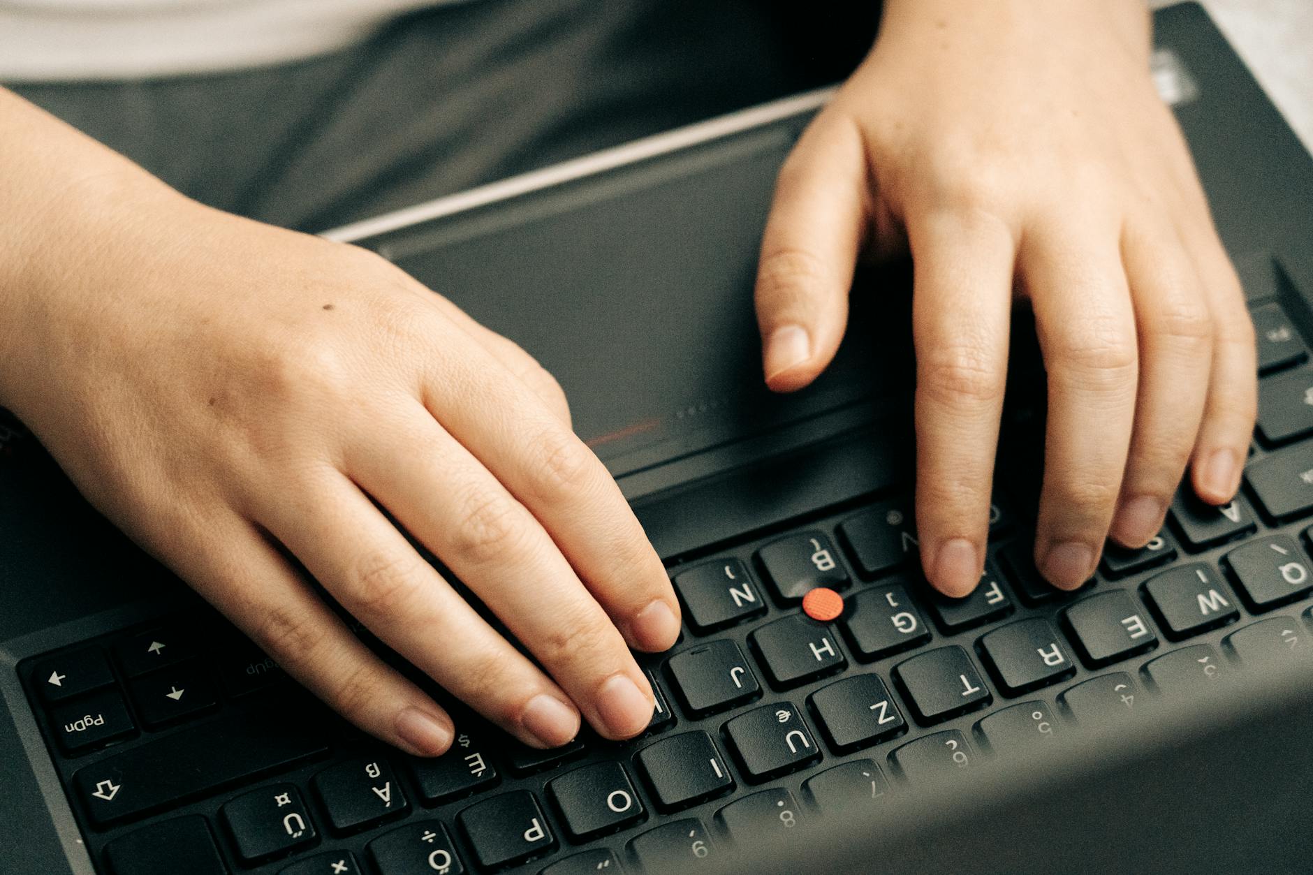 Close-up view of laptop keyboard with hands typing, representing digital marketing work and hashtag research