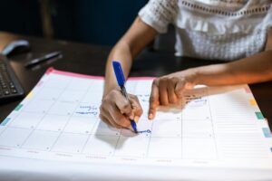 Person planning content calendar with colorful sticky notes and markers on desk
