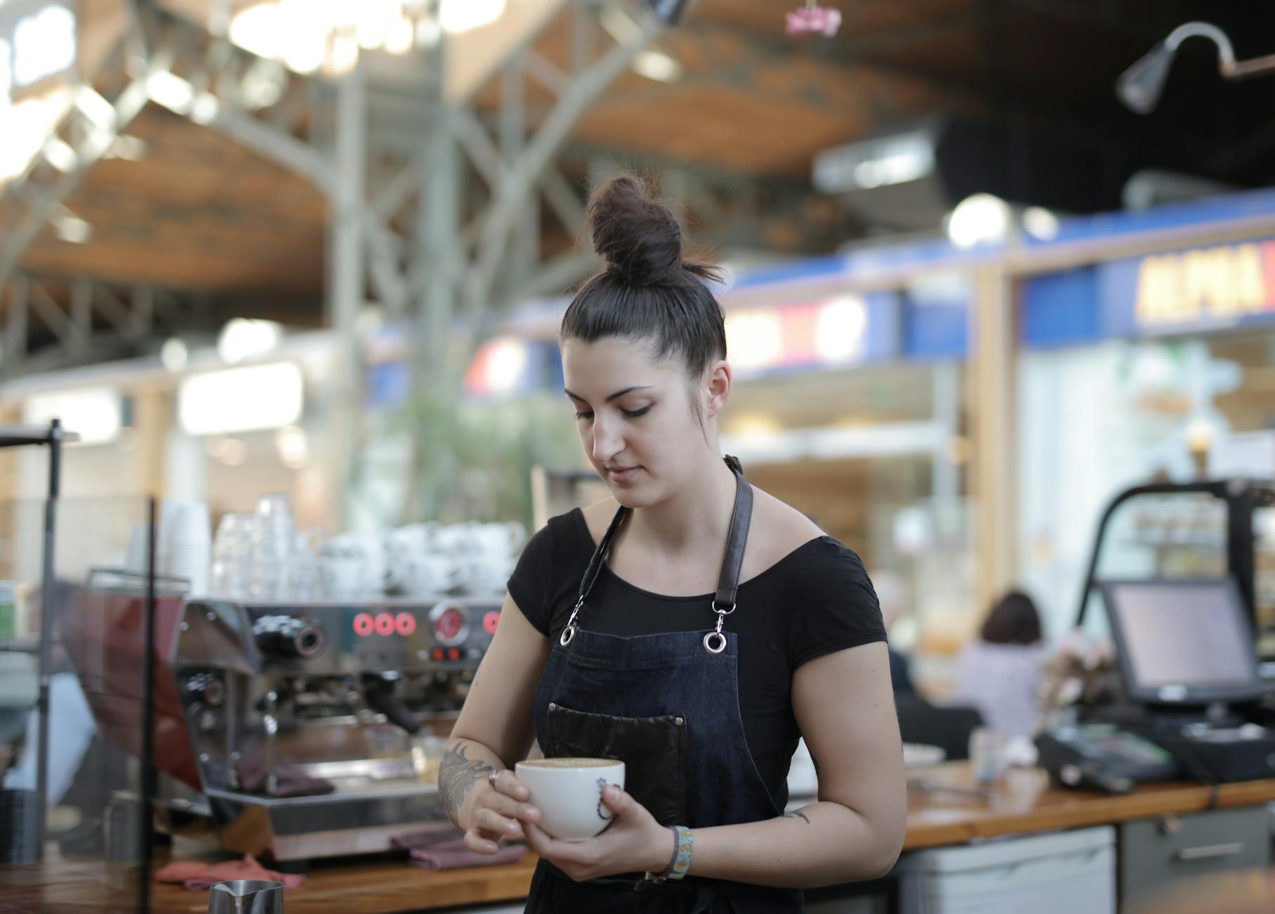 Friendly barista handing coffee to smiling customer through drive-thru window