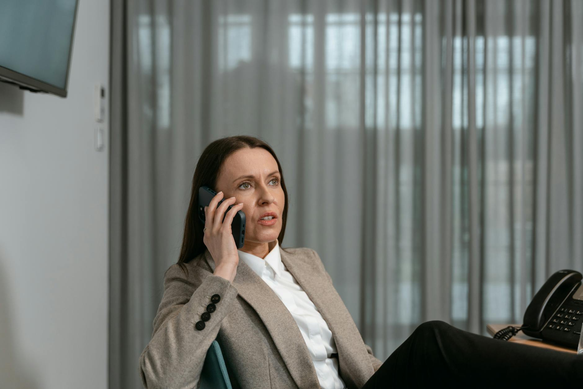 Young woman looking at smartphone screen while holding beauty product
