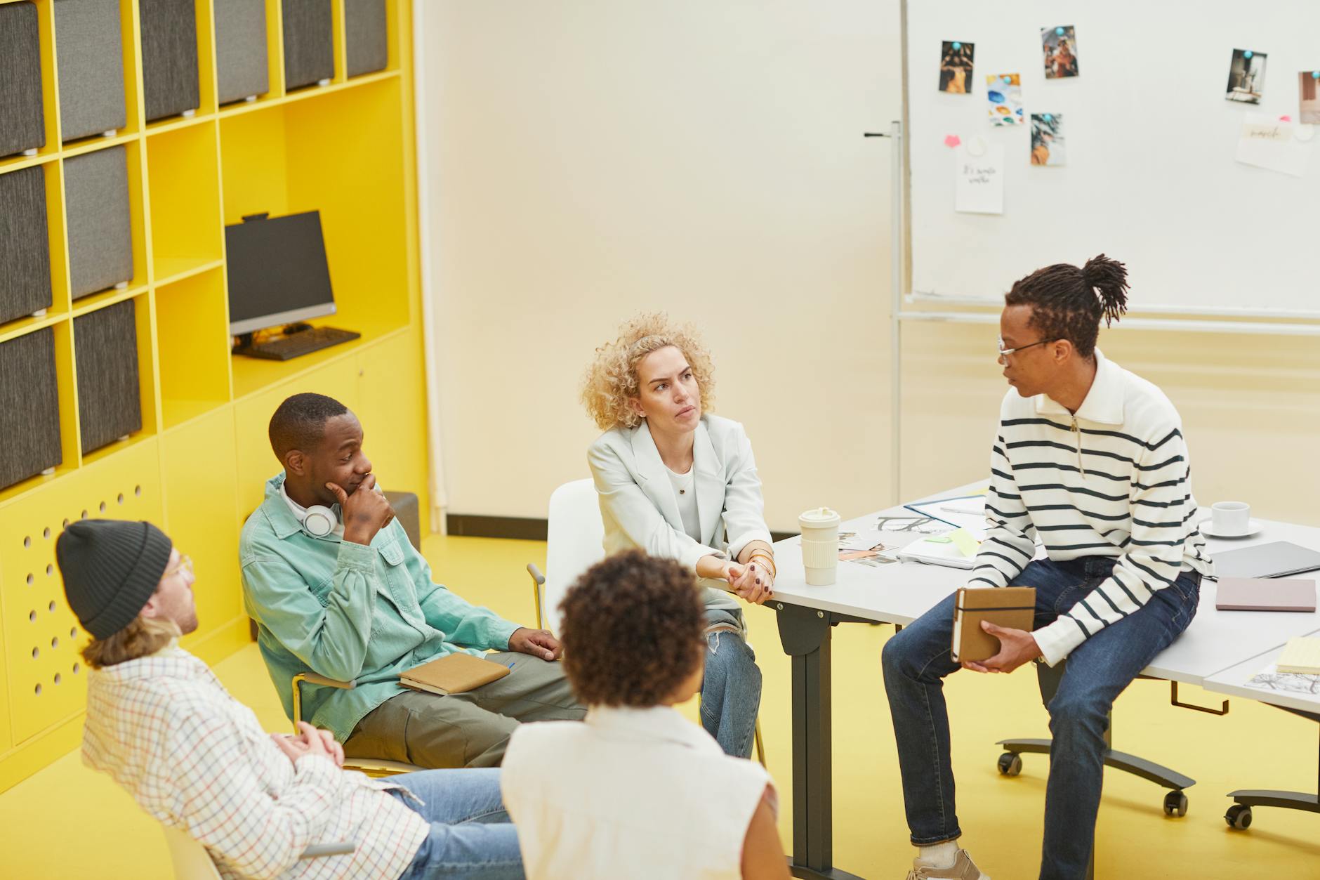 Creative professionals collaborating on design projects around a conference table with laptops
