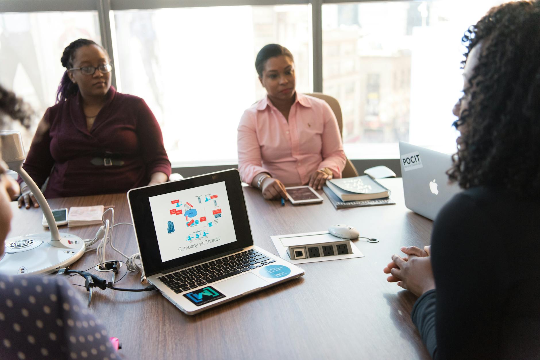 Group of people collaborating around a table with laptops and documents in modern office setting