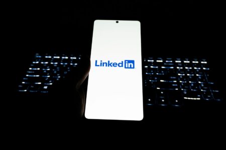 Person scrolling LinkedIn feed on a smartphone showing poll content