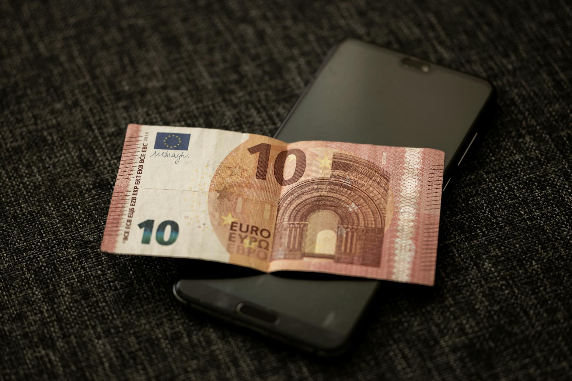 Smartphone displaying financial app with cash nearby, representing digital monetization