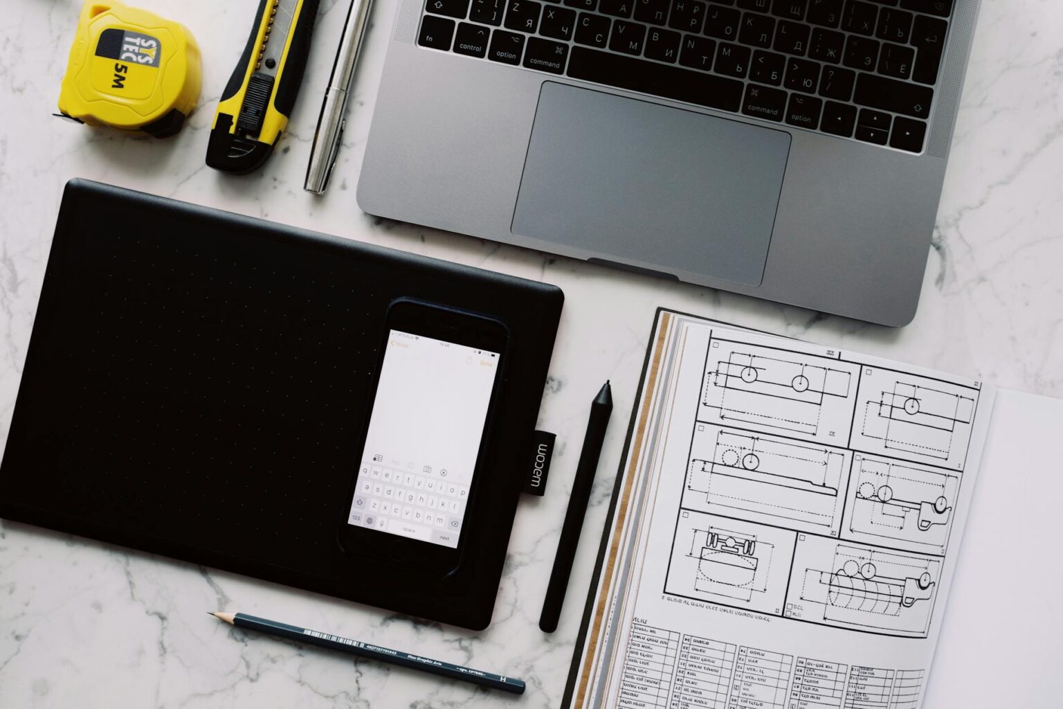 A clean desk workspace with a laptop showing a graphic design interface