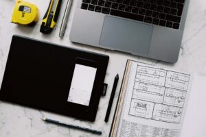A clean desk workspace with a laptop showing a graphic design interface