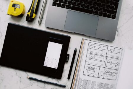 A clean desk workspace with a laptop showing a graphic design interface