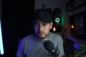 A content creator working at a desk with a monitor showing a video platform dashboard