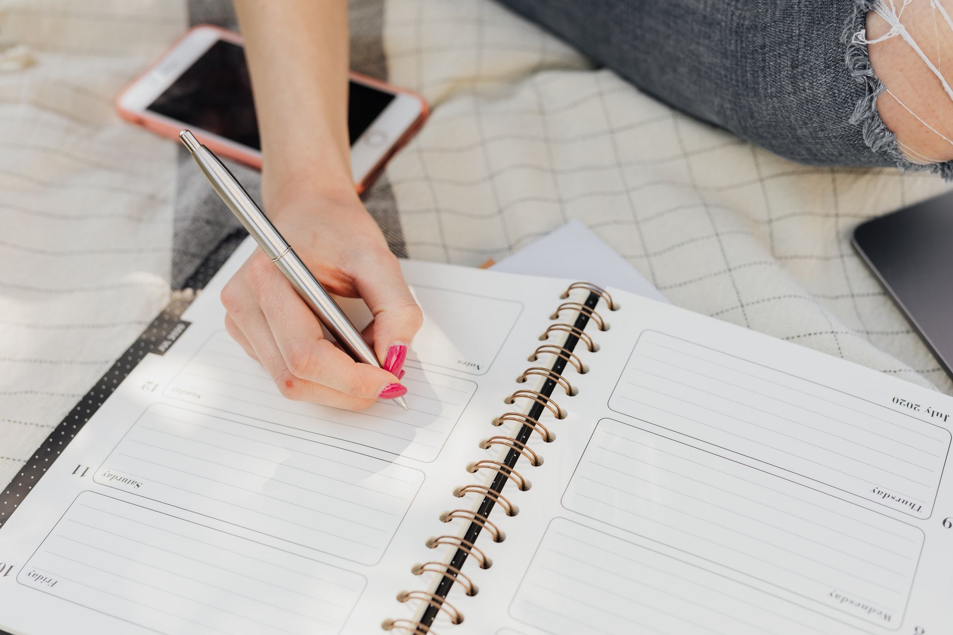 Open notebook with planning notes beside a laptop on a work desk