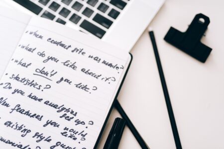 A creator working at a desk with a laptop and project notes spread out