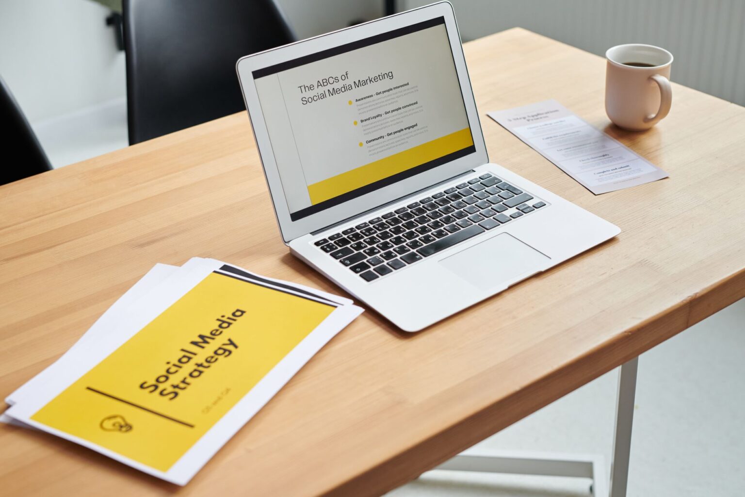A clean marketing workspace with a laptop showing ad creative examples on screen