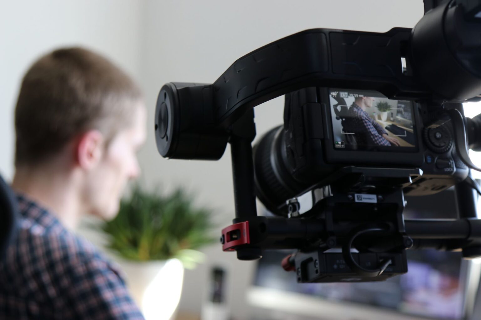 A marketing professional reviewing video content on a laptop in a modern office setting