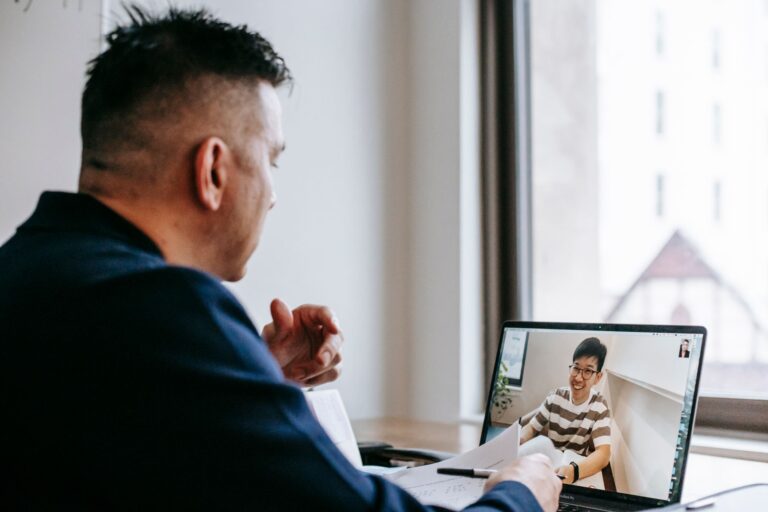 Two professionals on a video call reviewing notes on their screens
