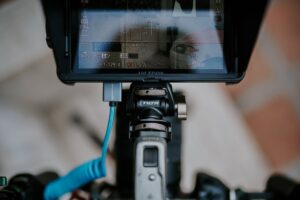 A video creator recording content at a desk with a camera and monitor setup