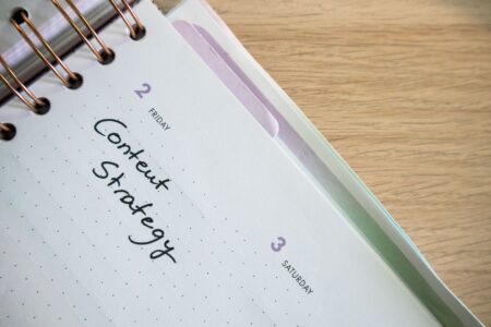 A content calendar spread open on a desk next to a laptop showing social media scheduling