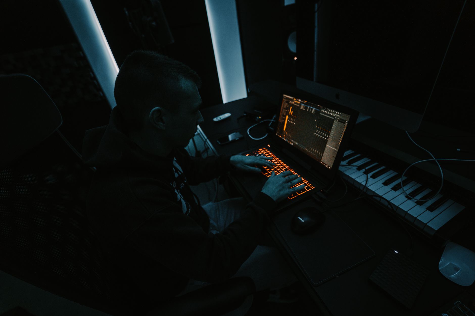 Person editing audio waveforms on a laptop screen in a studio environment