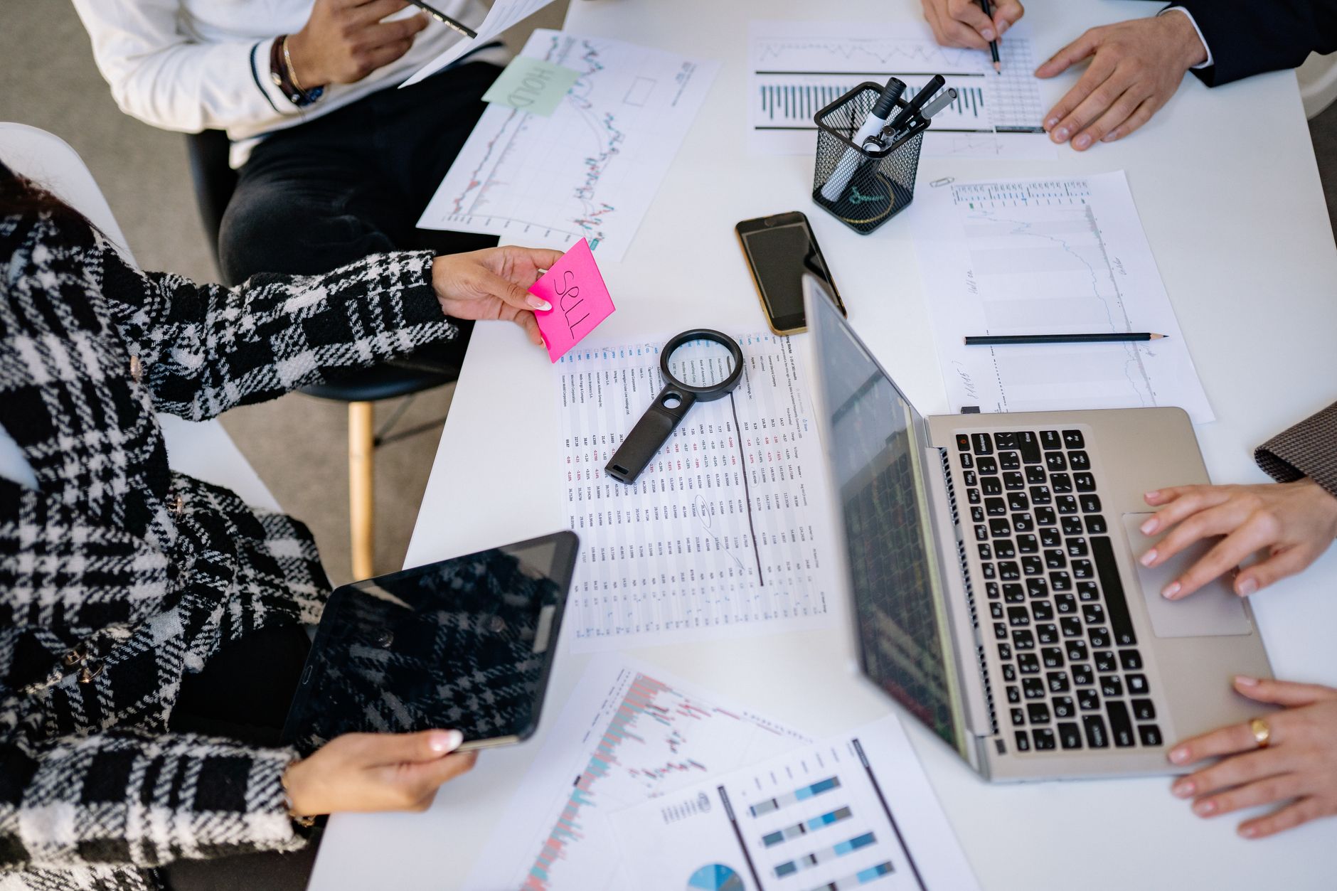 Marketing team members working together at a shared office desk with laptops open
