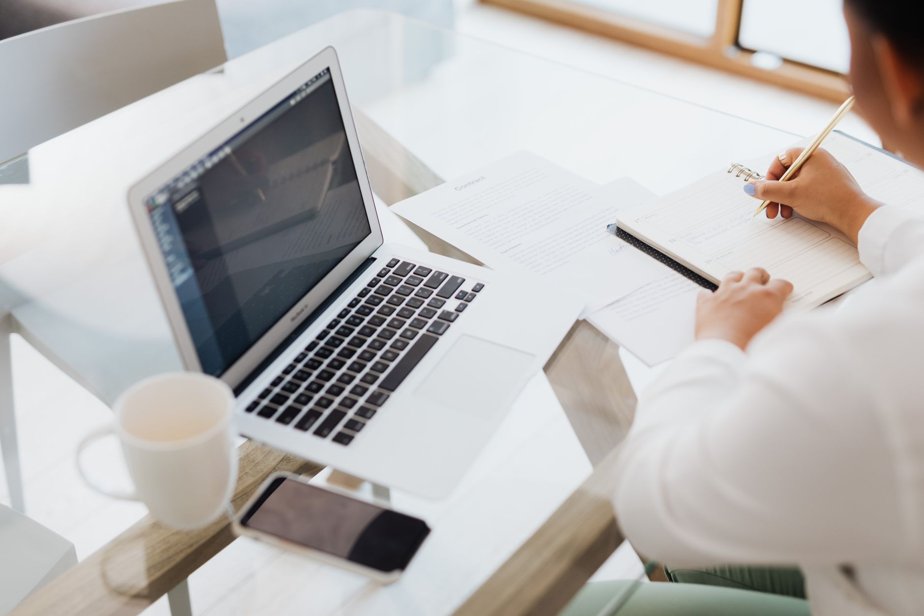 Person writing content on a laptop in a modern office workspace