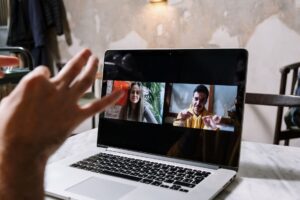 Person on a video call taking notes on a laptop during a remote meeting