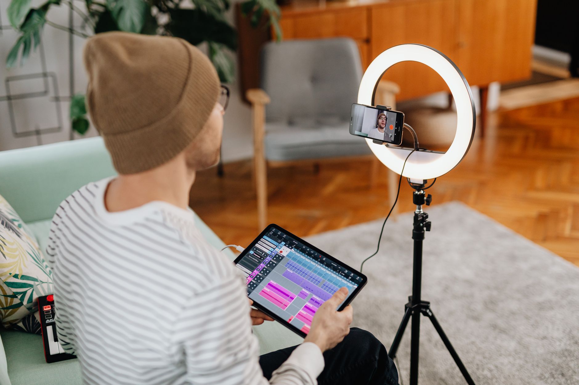 A video creator working at a desk with a camera and laptop in a home studio setup