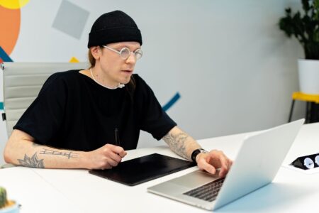 A designer working on social media content using a laptop at a clean desk workspace