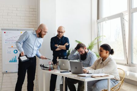 Social media team collaborating around a shared digital workspace on laptops