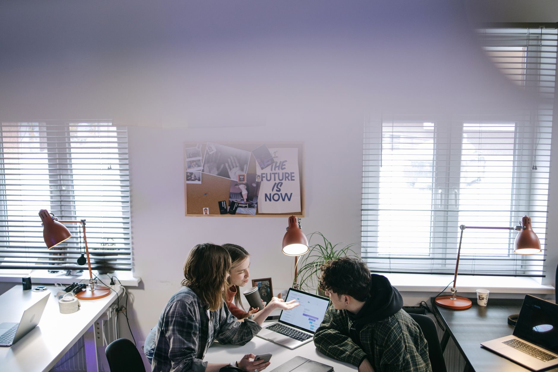 Agency team members collaborating around a computer screen reviewing social media content