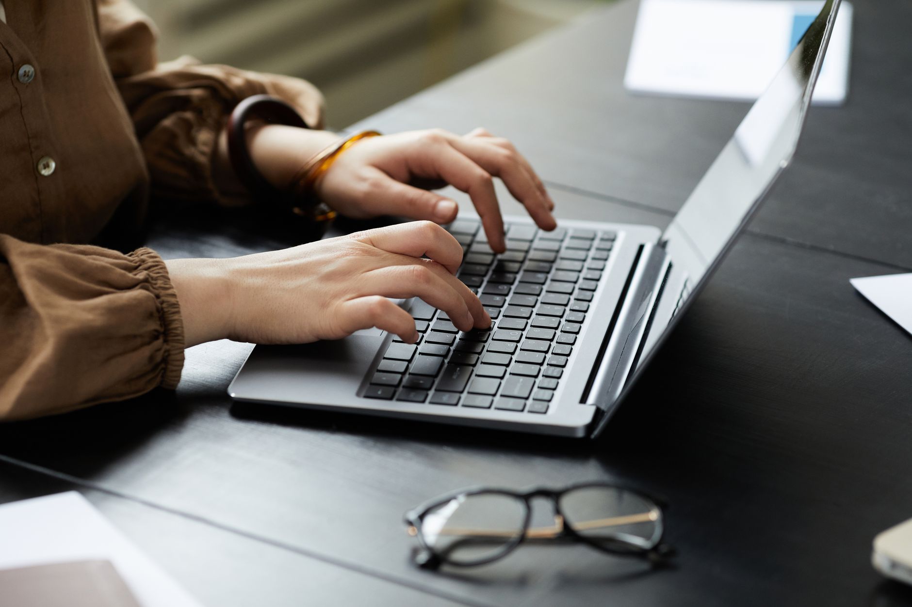 A content creator typing on a laptop while managing an online newsletter