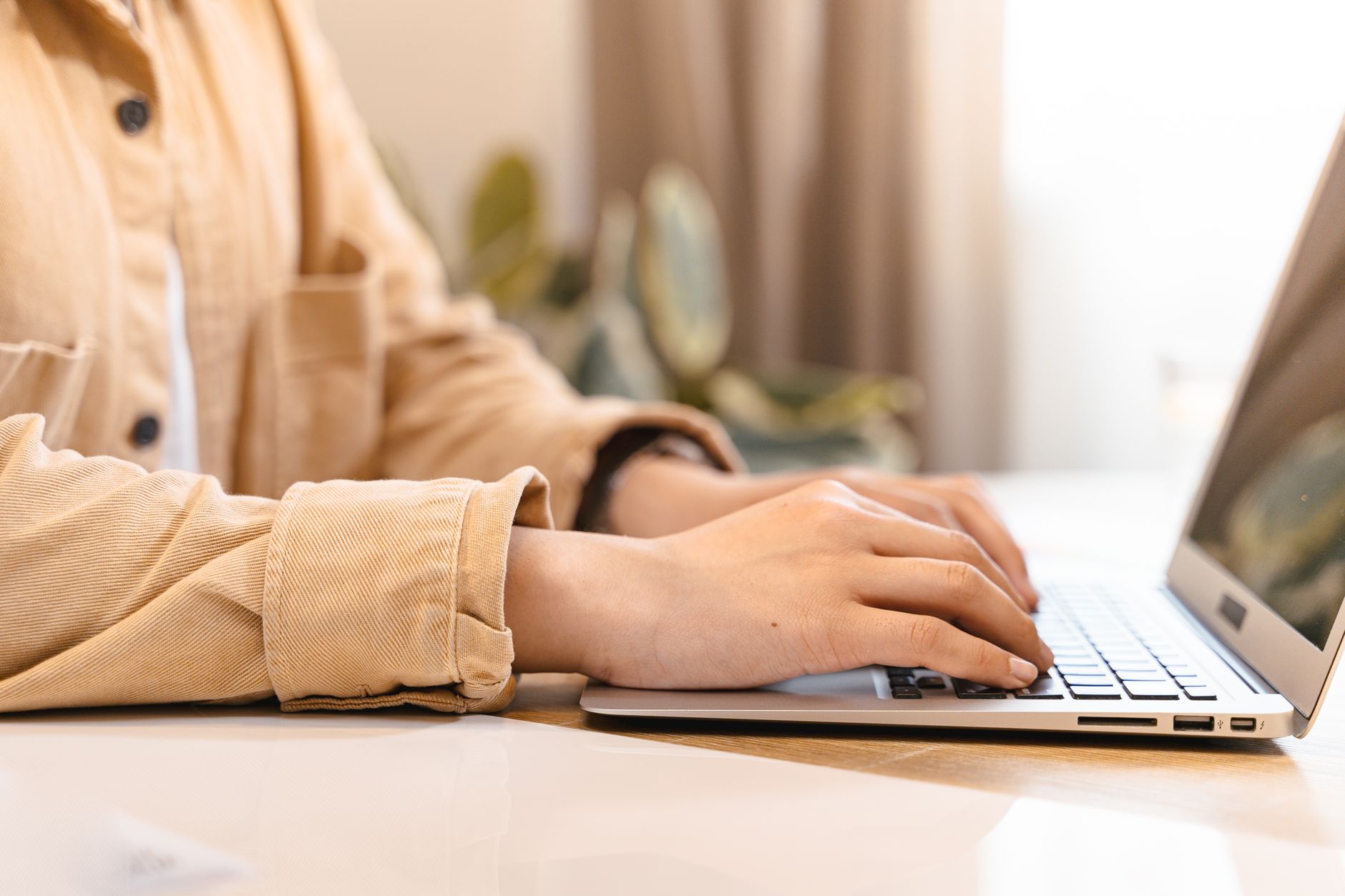 A content creator typing a script on a laptop at a minimalist workspace