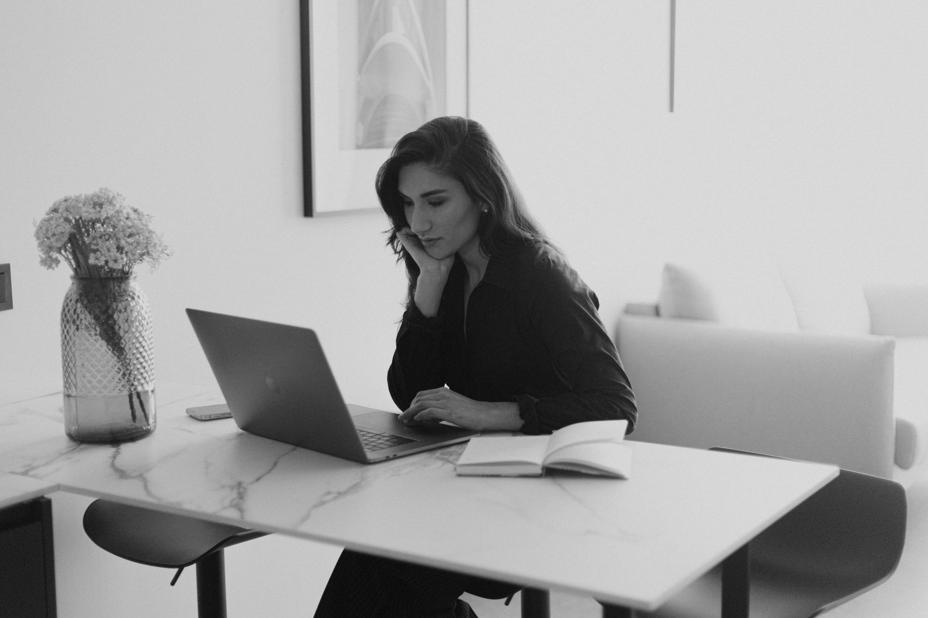A woman working on a laptop, reviewing a content project management tool