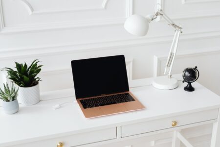 A blogger working at a home desk with a laptop and notebook open